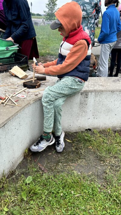 Chłopiec batonujący szczapkę drewna